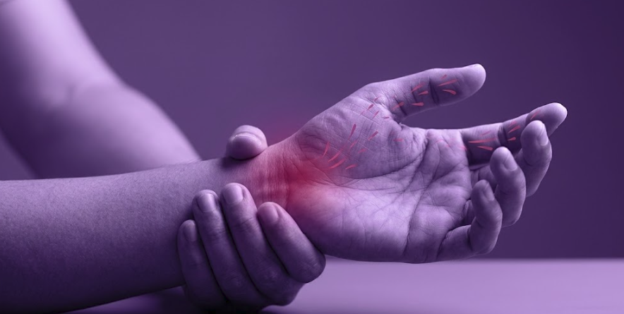 Masajes En Elche Túnel Carpiano: La solución definitiva al hormigueo de manos 2 Primer plano de una mano y muñeca con iluminación morada mostrando el punto de dolor del síndrome del túnel carpiano para un tratamiento de quiromasaje en Elche.
